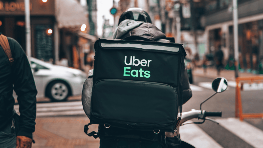 Repartidor de comida, que trabaja para la app de delivery Uber Eats, sobre una moto.