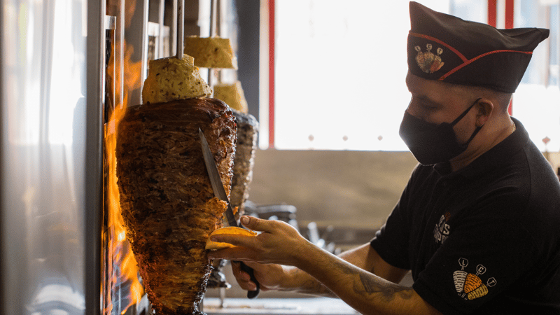 hombre preparando un taco al pastor 