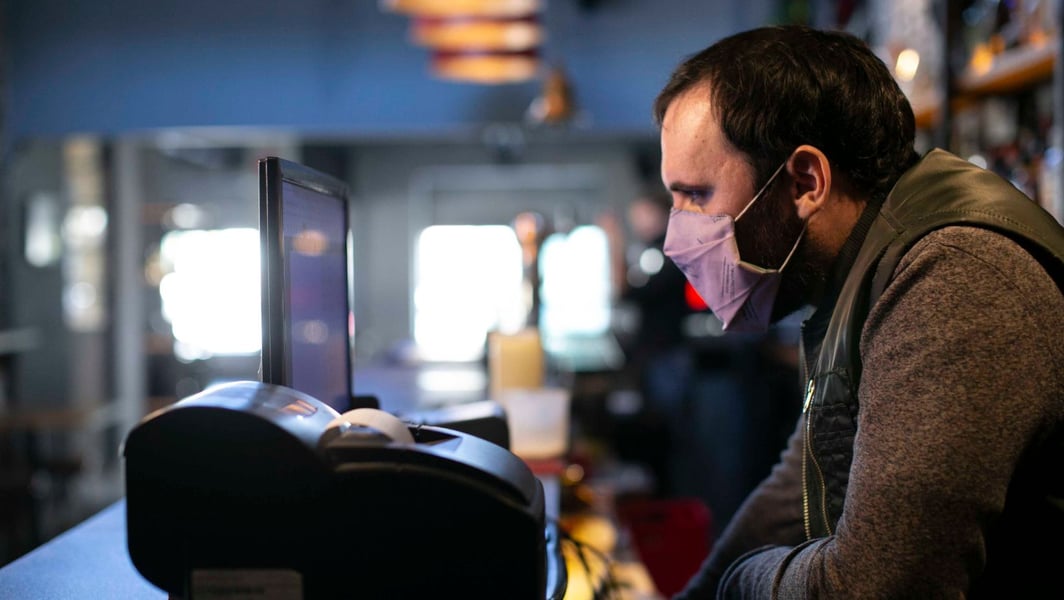 Hombre mirando una computadora en su bar 