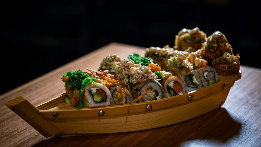 Varias piezas de sushi presentadas en un barco de madera. 