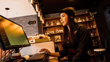 Mujer trabajando en una cafetería y mirando su computador