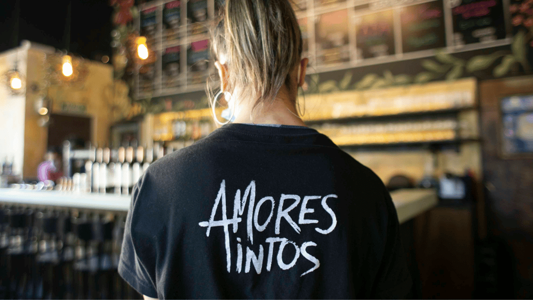 Camarera de Amores Tintos de espalda, mostrando una remera con la marca del wine bar. 