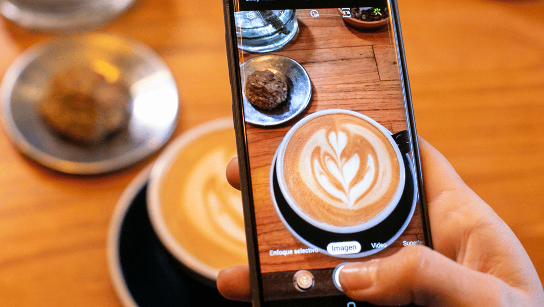 persona filmando una taza de café con su teléfono móvil
